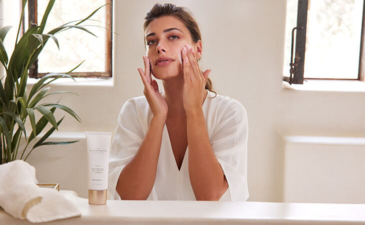 A woman applies The Ritual of Namaste skin-brightening exfoliator, part of her daily skincare routine
